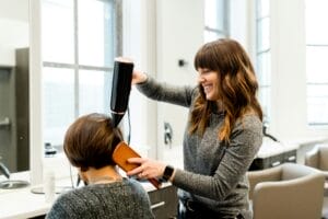 Friseurin stylt die Haare einer Kundin im Friseursalon