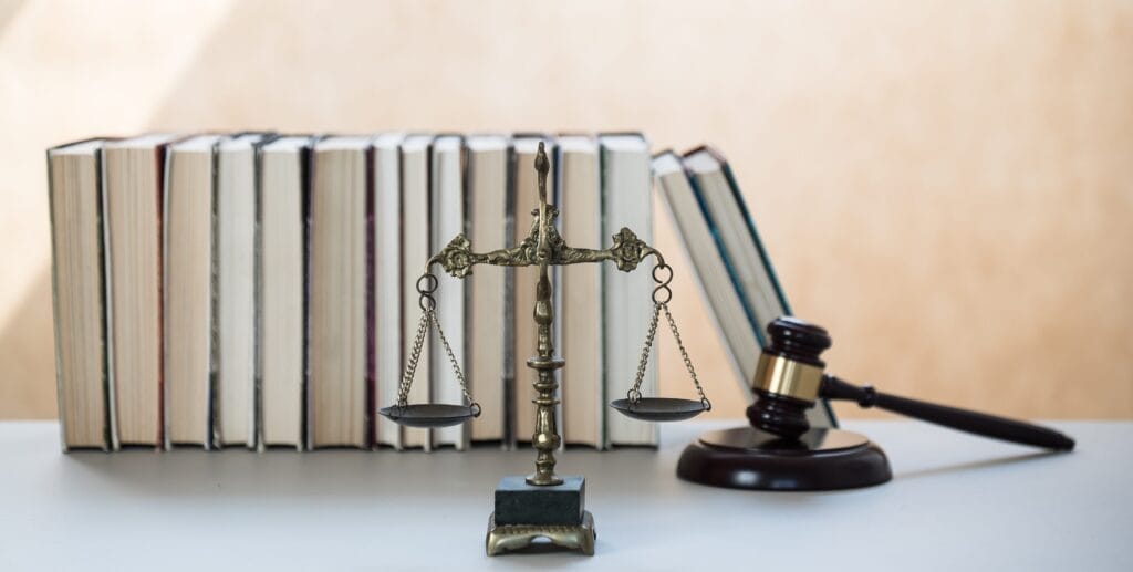 Richterwaage, Waage der Gerechtigkeit im Vordergrund, Hammer für Gerichtsverhandlungen und Bücher im Hintergrund